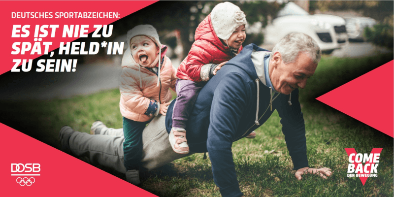 Ein älterer Mann spielt mit zwei Kindern im Gras und genießt die Zeit im Freien.