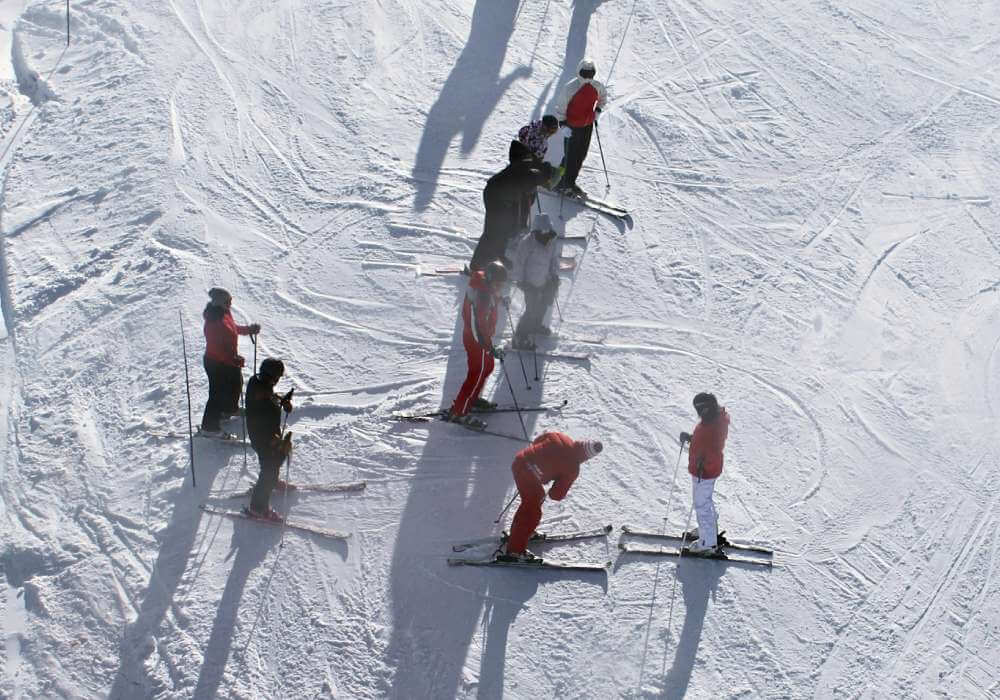 Eine Gruppe von Menschen, die auf Skiern steht und bereit ist, die Piste hinunterzufahren.